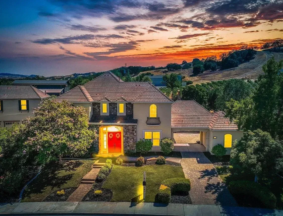 An aerial view of a large house with a sunset in the background.