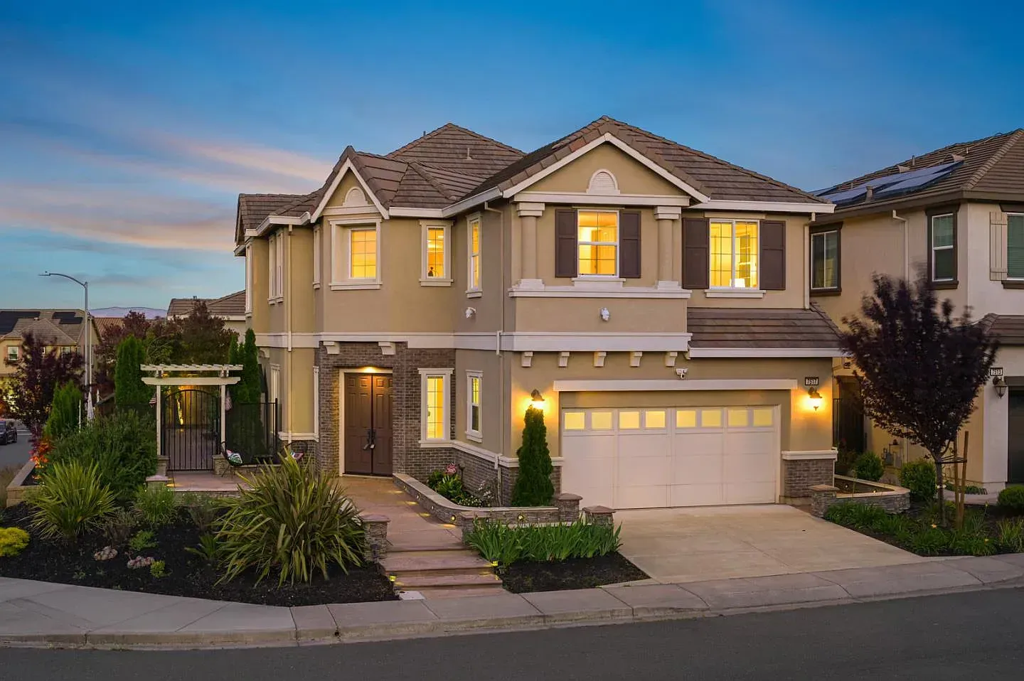 A large house with a white garage door is lit up at night.