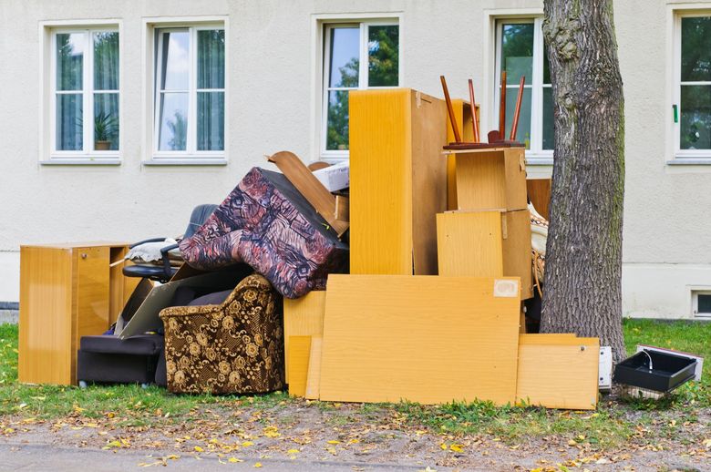 A pile of junk is sitting next to a tree in front of a building.