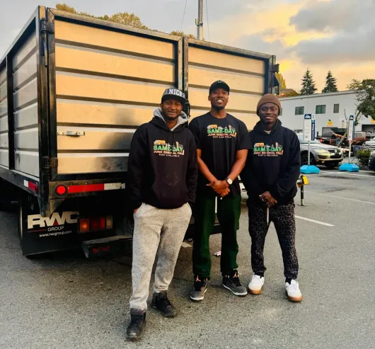 Three men standing in front of a truck that says fwc