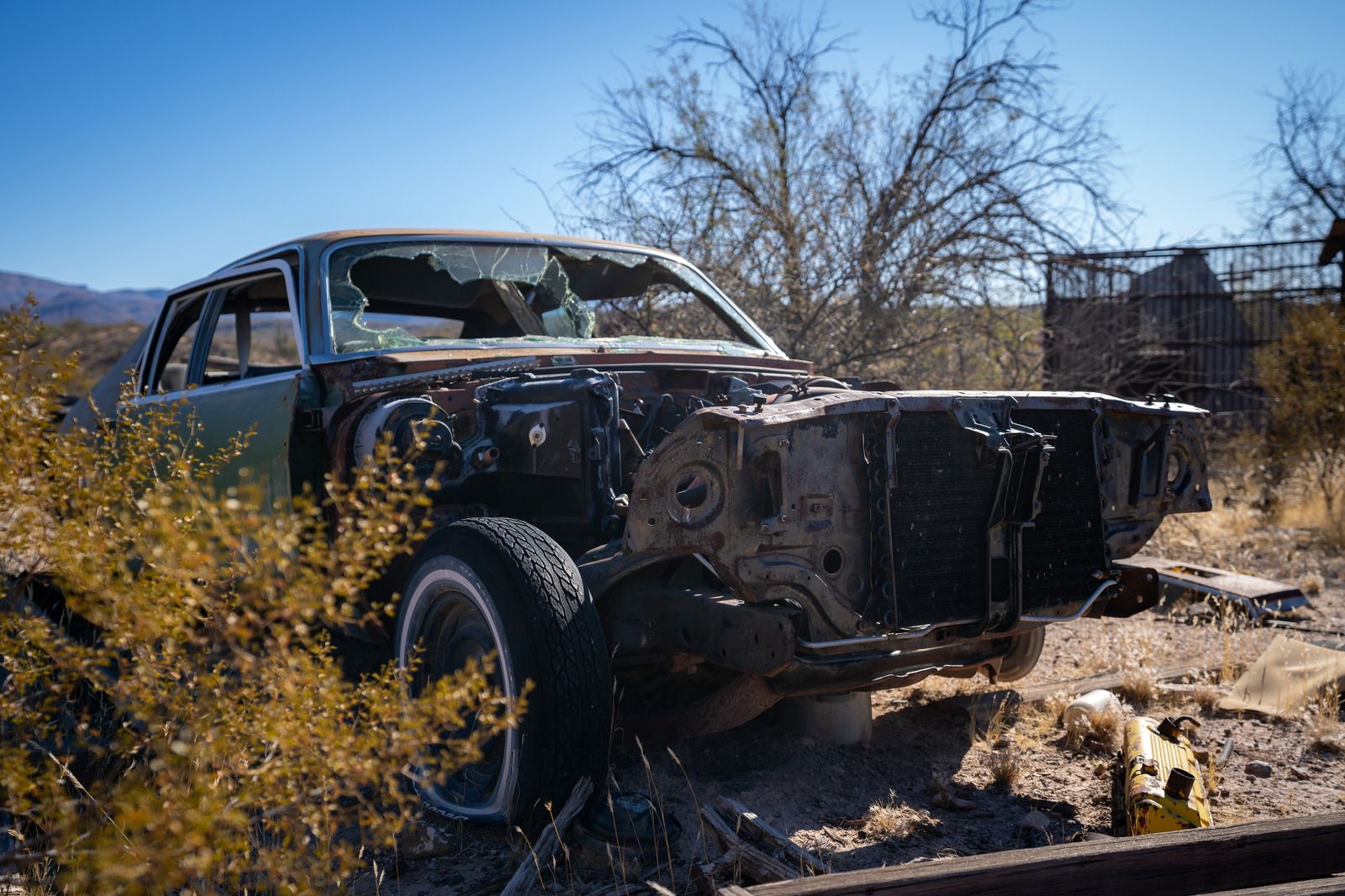 An old car with a broken windshield is sitting in the desert.
