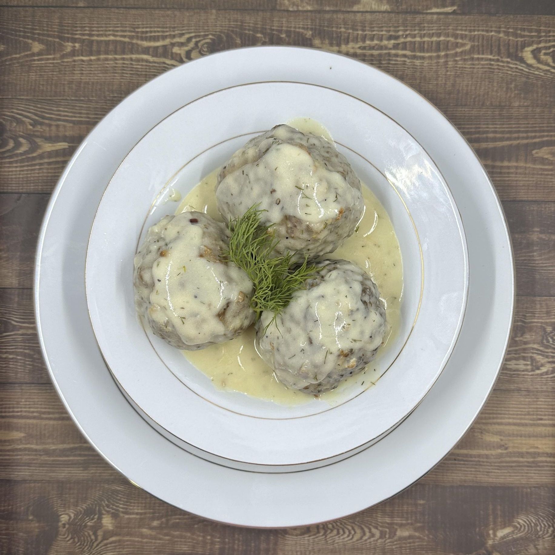 A white plate topped with meatballs and sauce on a wooden table.