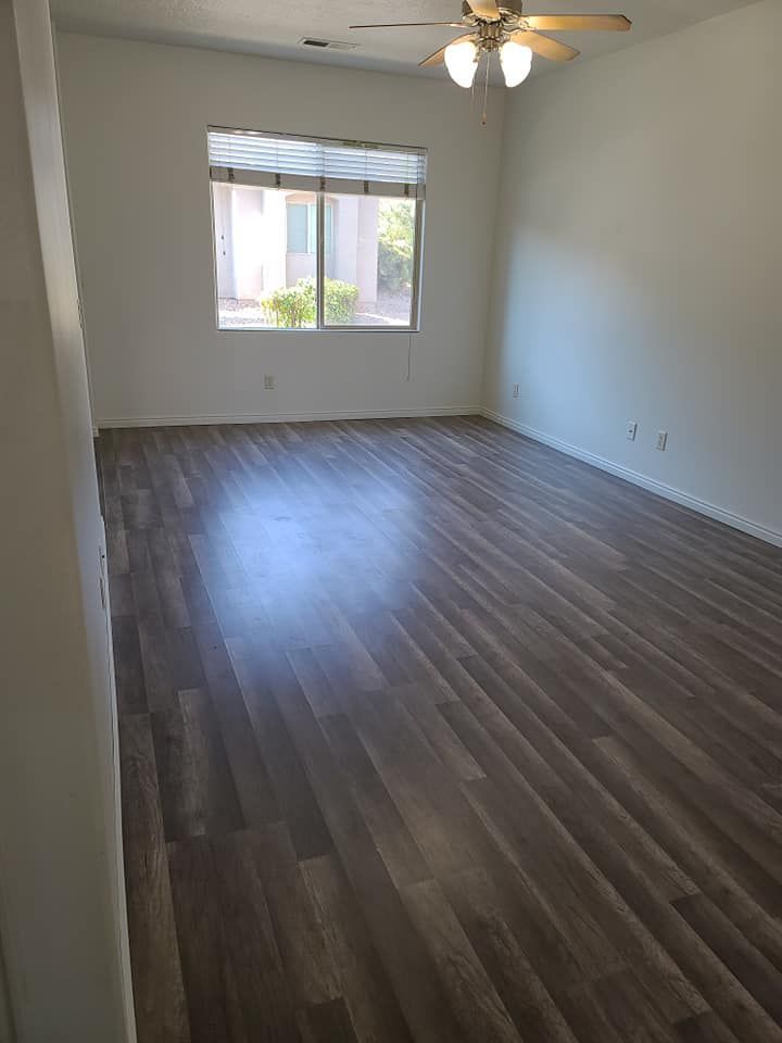 An empty living room with hardwood floors and a ceiling fan.