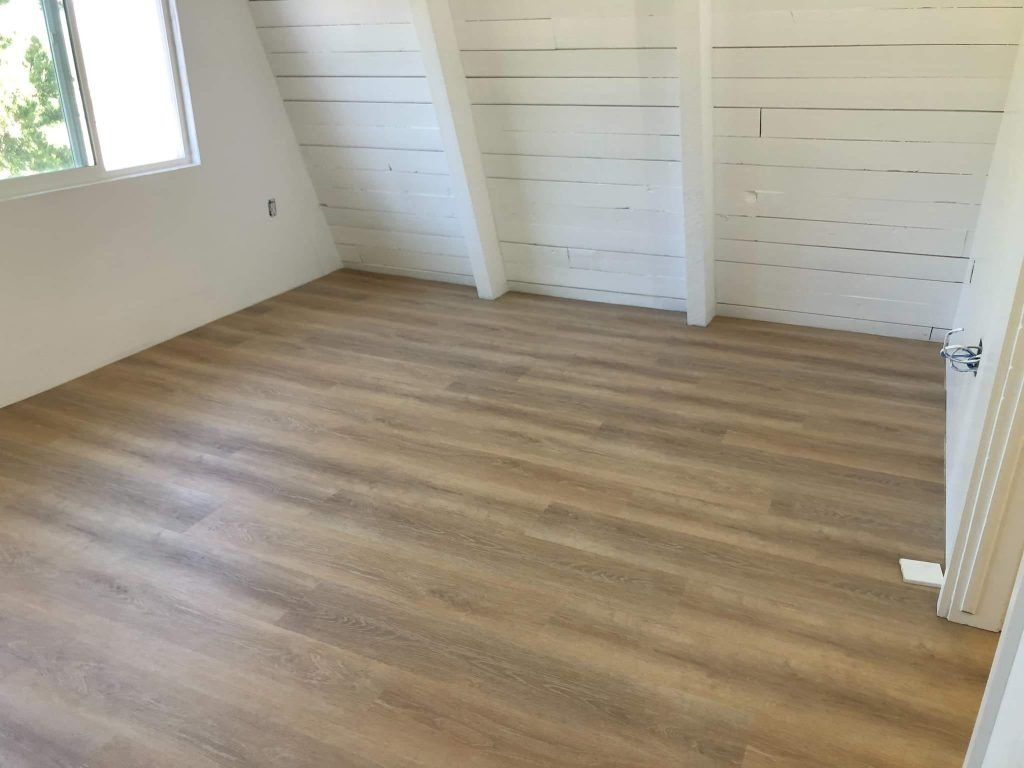 An empty room with a wooden floor and white walls.
