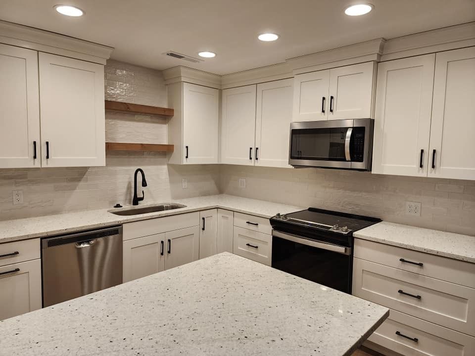 A kitchen with white cabinets , stainless steel appliances , and a large island.