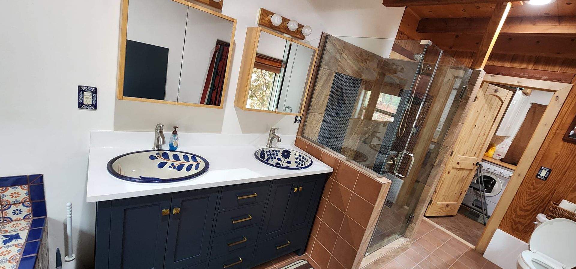 A bathroom with two sinks , two mirrors and a walk in shower.