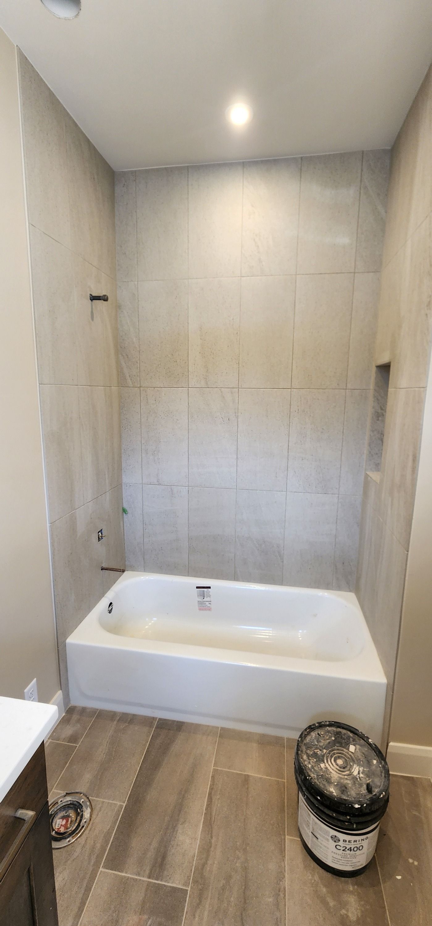 A bathroom with a bathtub and a bucket on the floor.