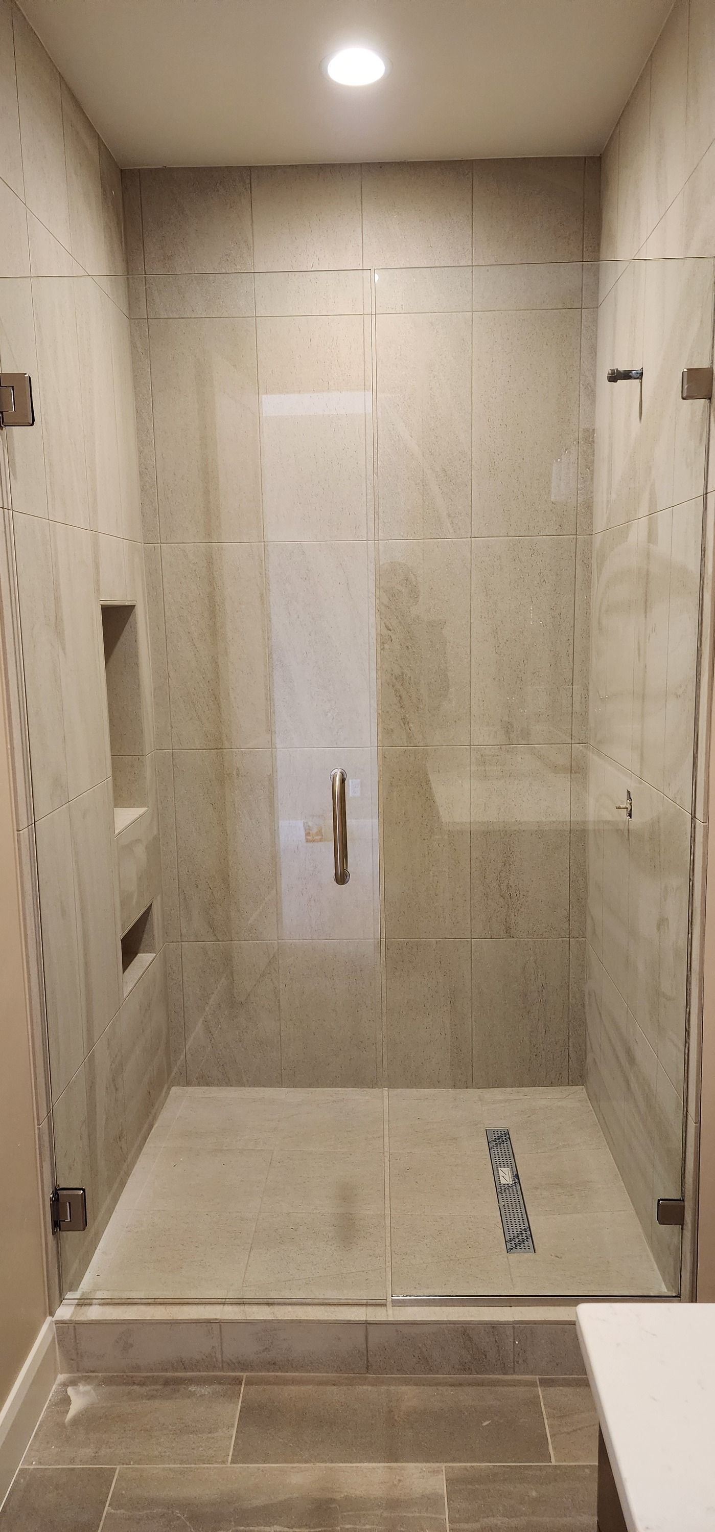 A bathroom with a walk in shower with a glass door.