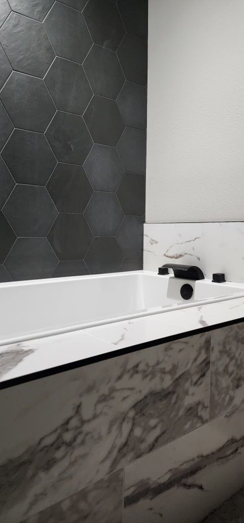 A bathroom with a bathtub , sink and mirror.