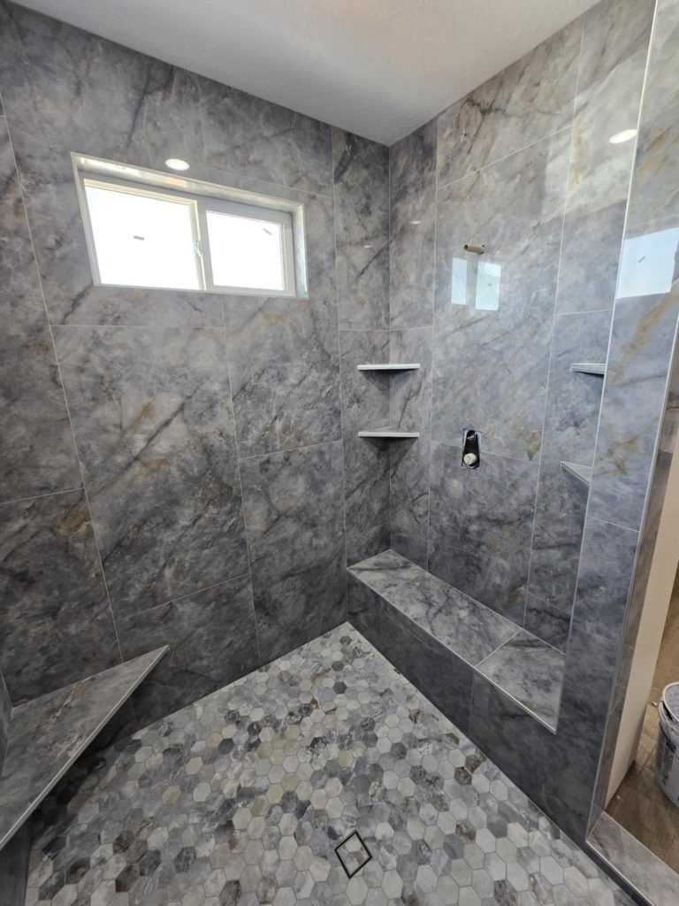 A bathroom with a walk in shower and a window.