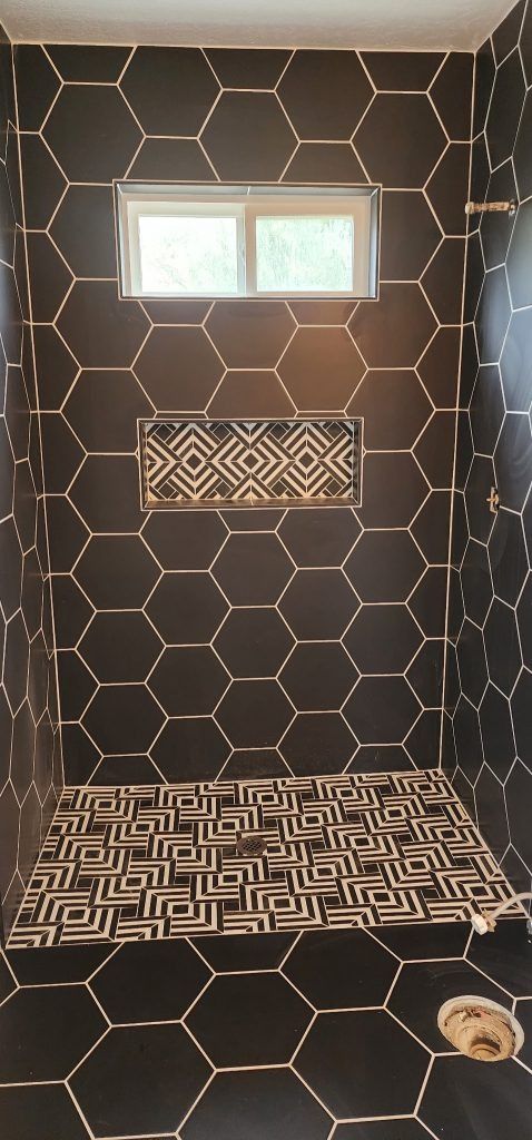 A shower with black tiles and a window.