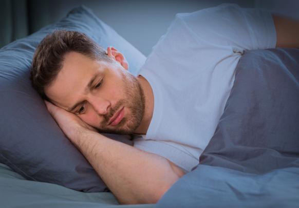 A man is sleeping in a bed with his head on a pillow.