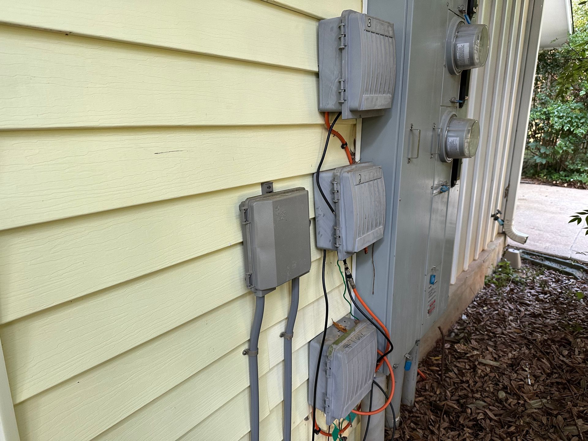 There are a lot of electrical boxes on the side of a house.
