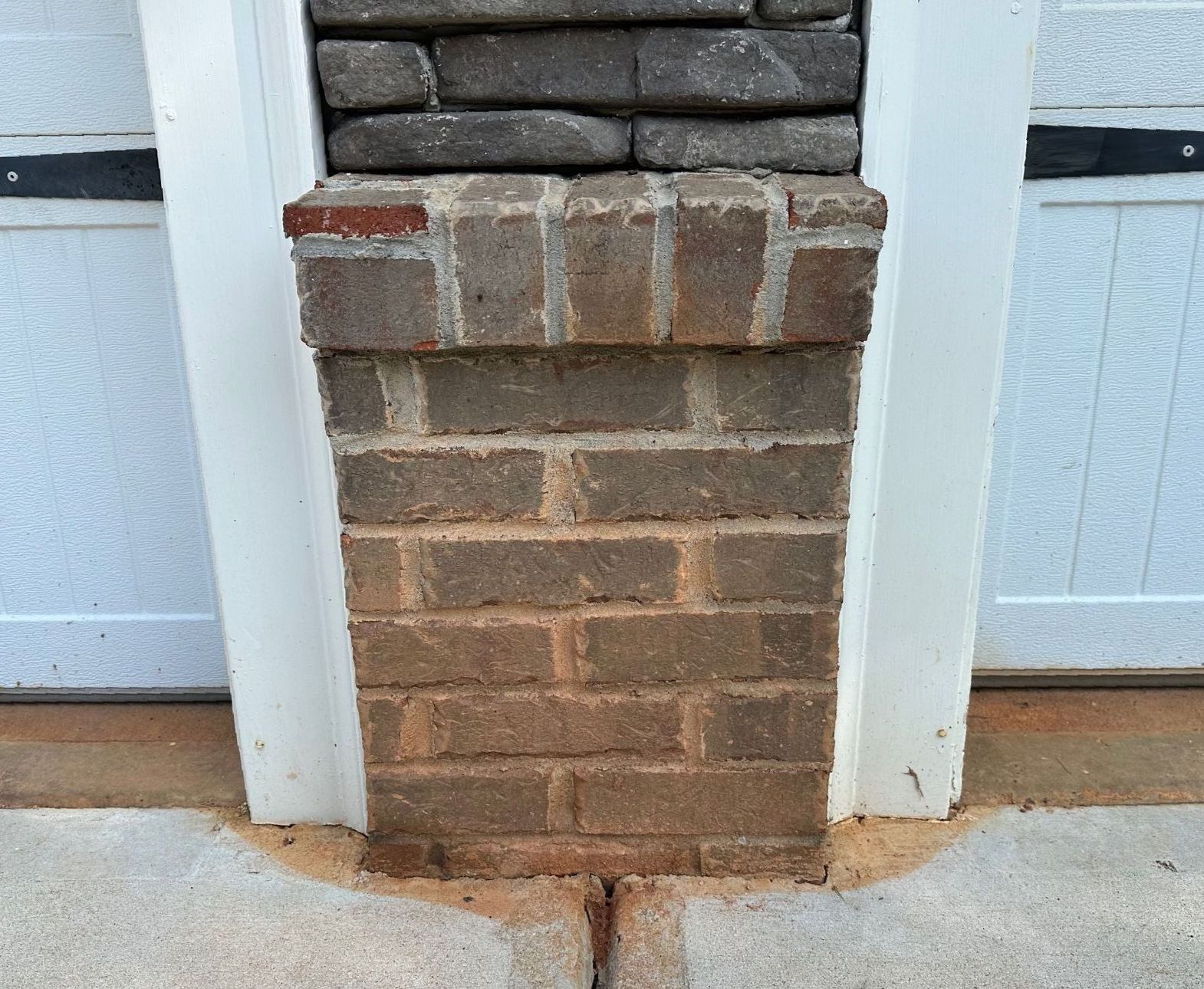 A brick chimney in front of a garage door