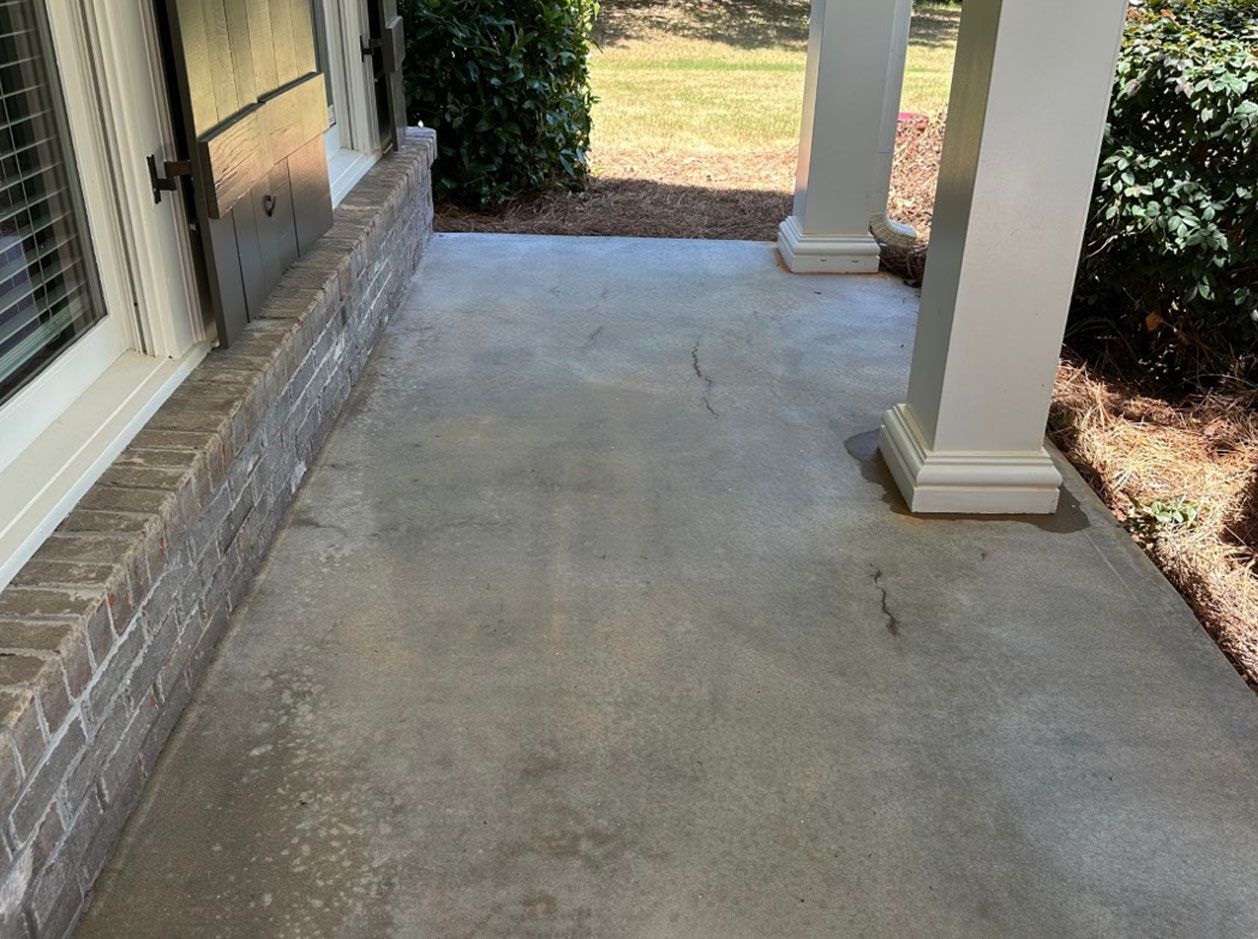 A concrete walkway leading to a porch of a house.