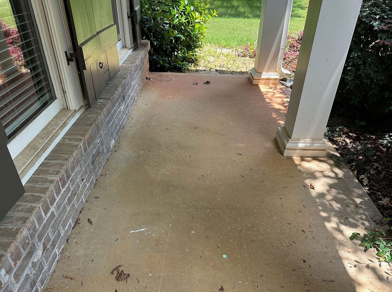 A dirty porch with a brick wall and a white pillar.