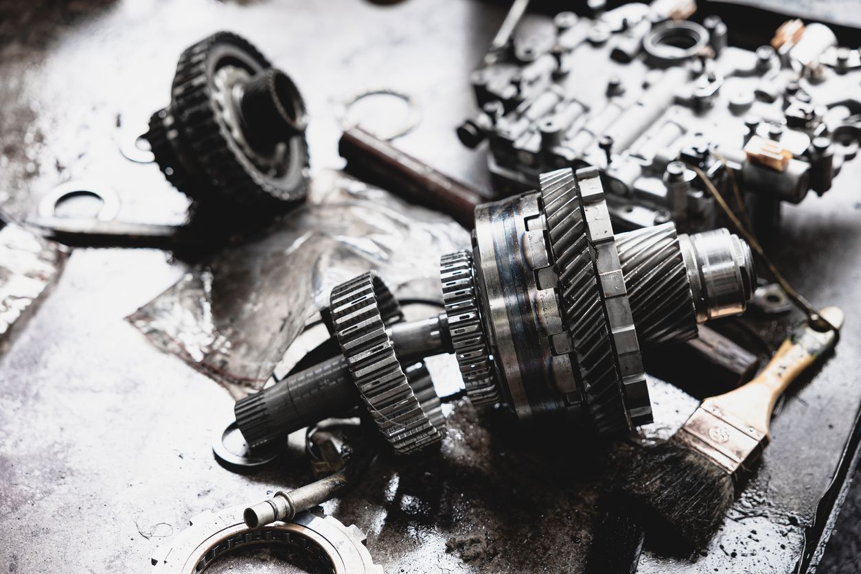 Scattered metal gears, bearings, and mechanical parts on a greasy workshop surface