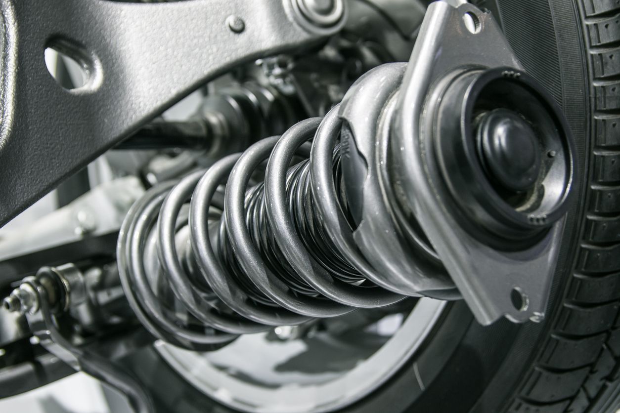 Close-up of a car suspension spring and shock absorber in metallic silver.