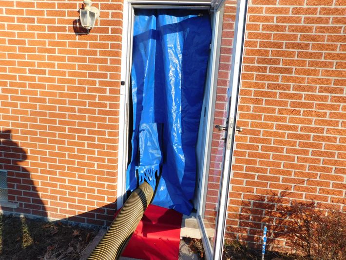 A person is cleaning a furnace with a vacuum cleaner.