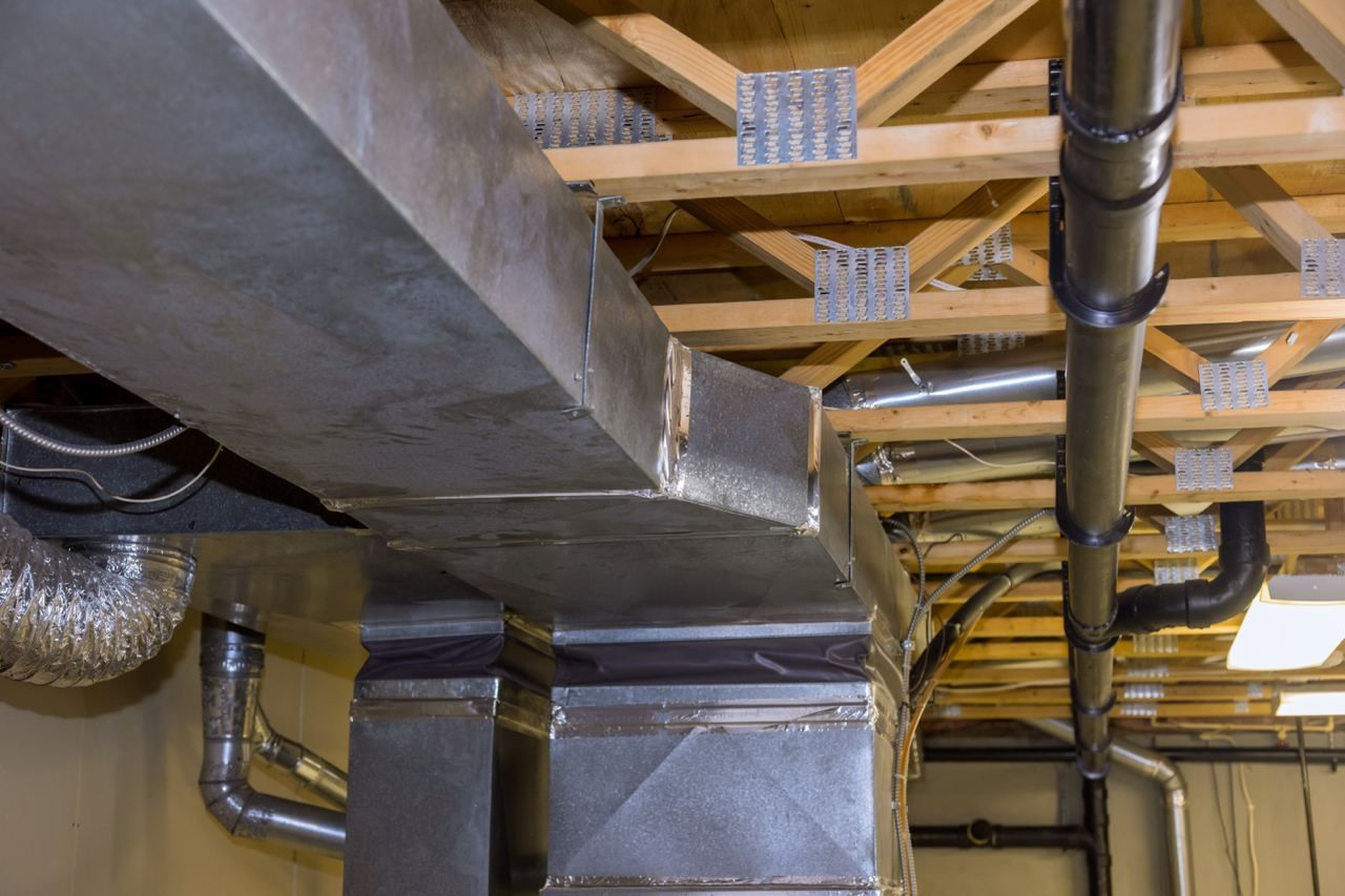 HVAC ductwork and plumbing pipes installed under a wooden ceiling.