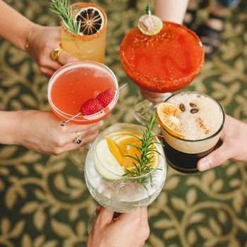 A group of people are holding glasses of different types of drinks.