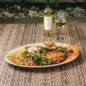 A plate of food with a bottle of wine and a glass of wine on a table.