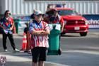 People wearing matching team shirts stand near a green bin and a red truck at an outdoor event.