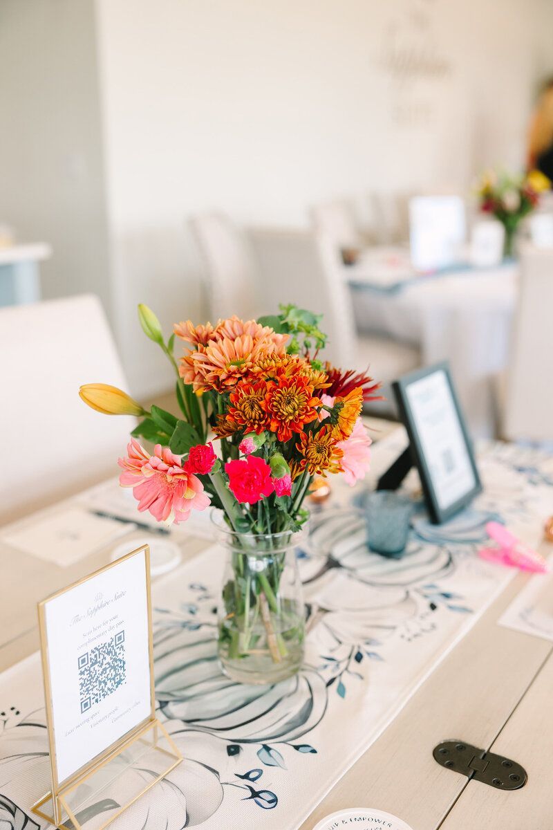 Flowers in vase on table with signs and decor.