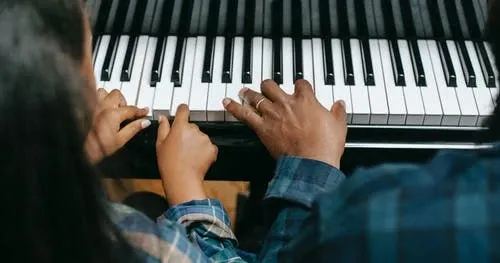 man teaching girl to play keyboard