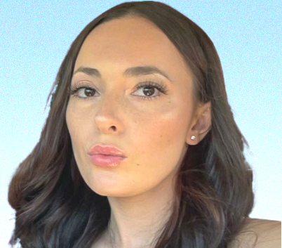 A woman with long brown hair and earrings is looking at the camera.