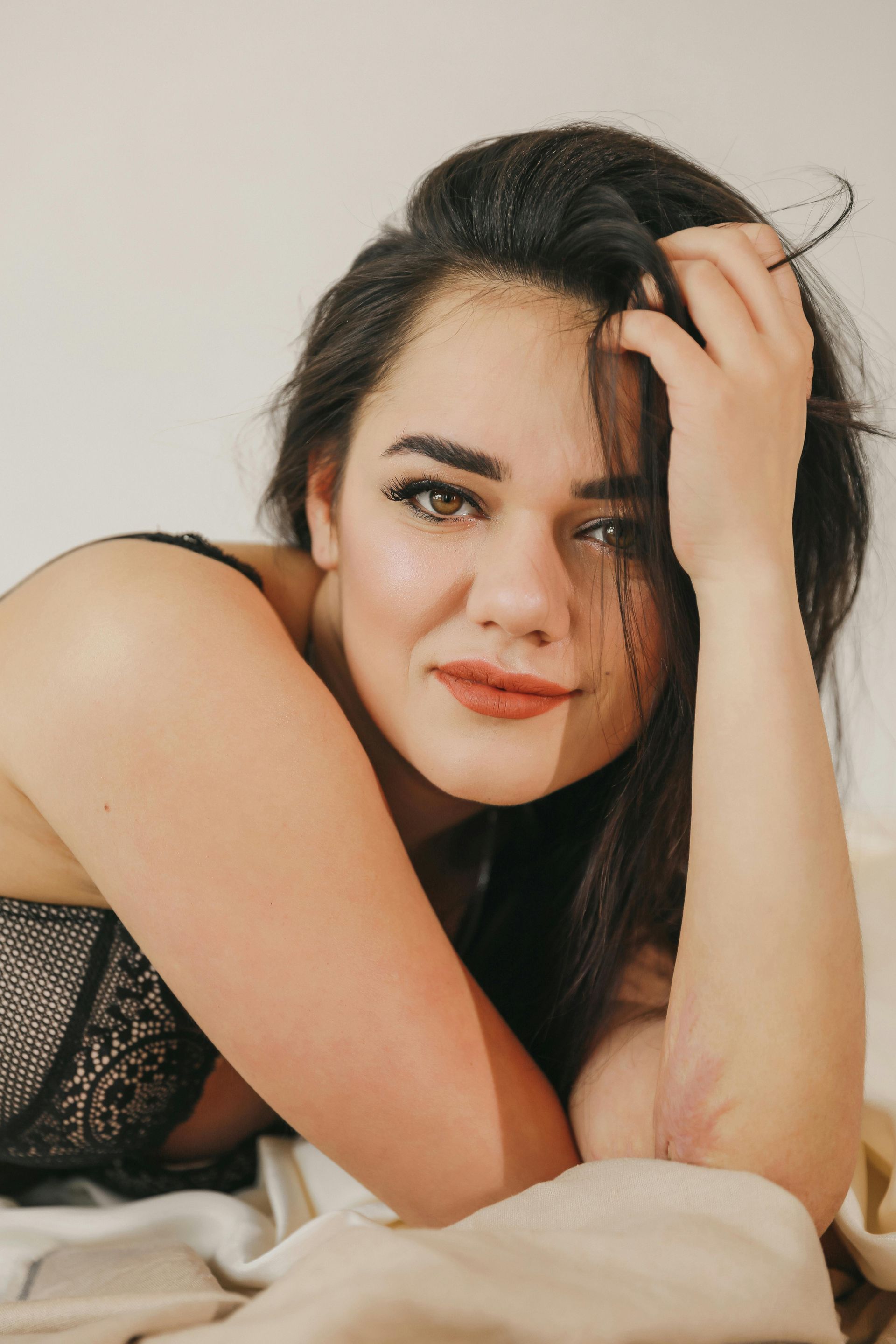 A woman wearing sunglasses and a red jacket is standing in front of a building.
