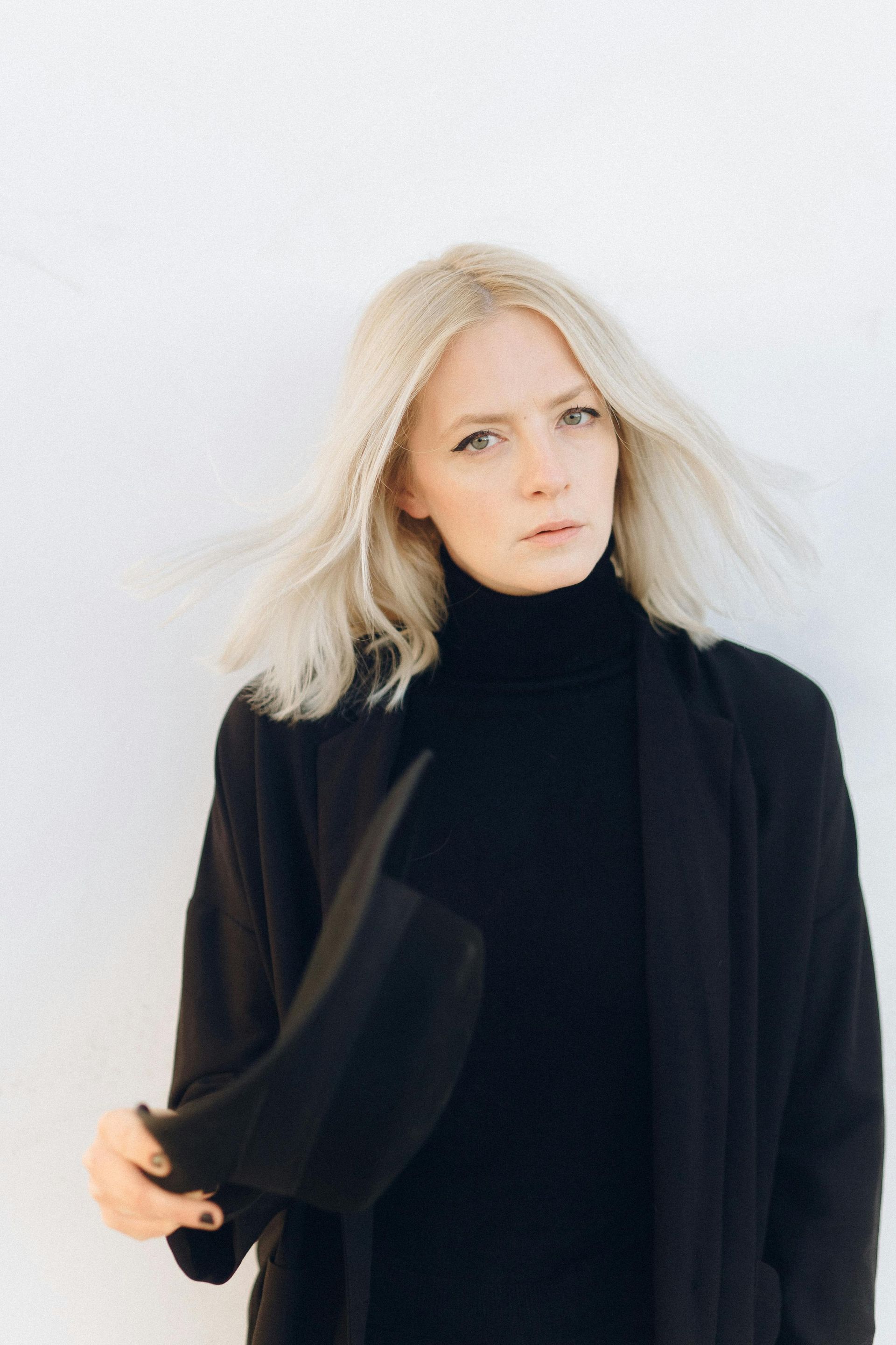 A close up of a blonde woman wearing a choker and a plaid shirt.