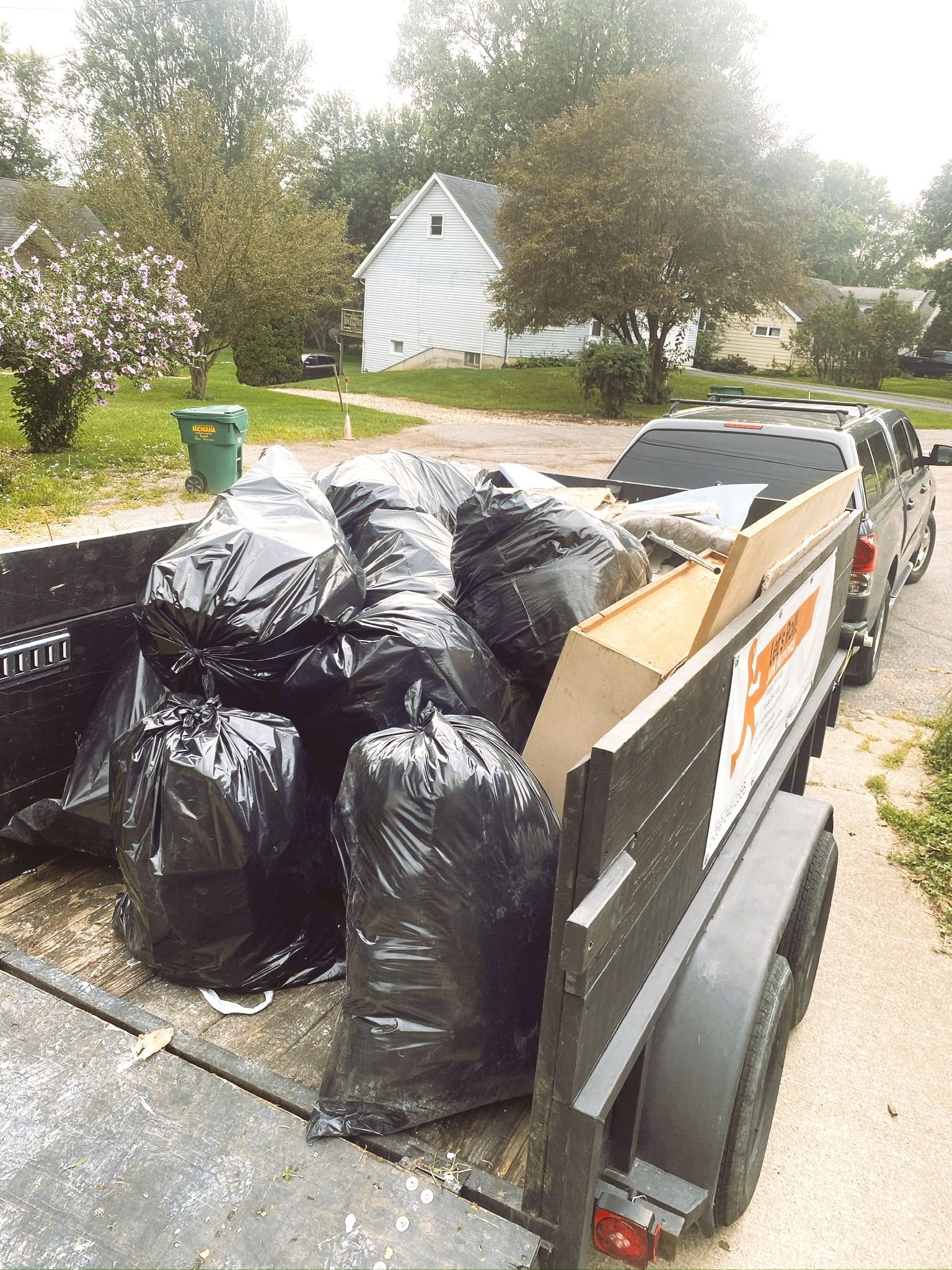 A truck with a trailer full of garbage bags
