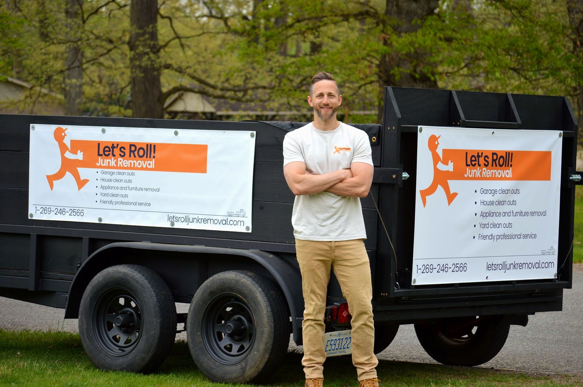 A man is standing in front of a dumpster that says let 's roll.