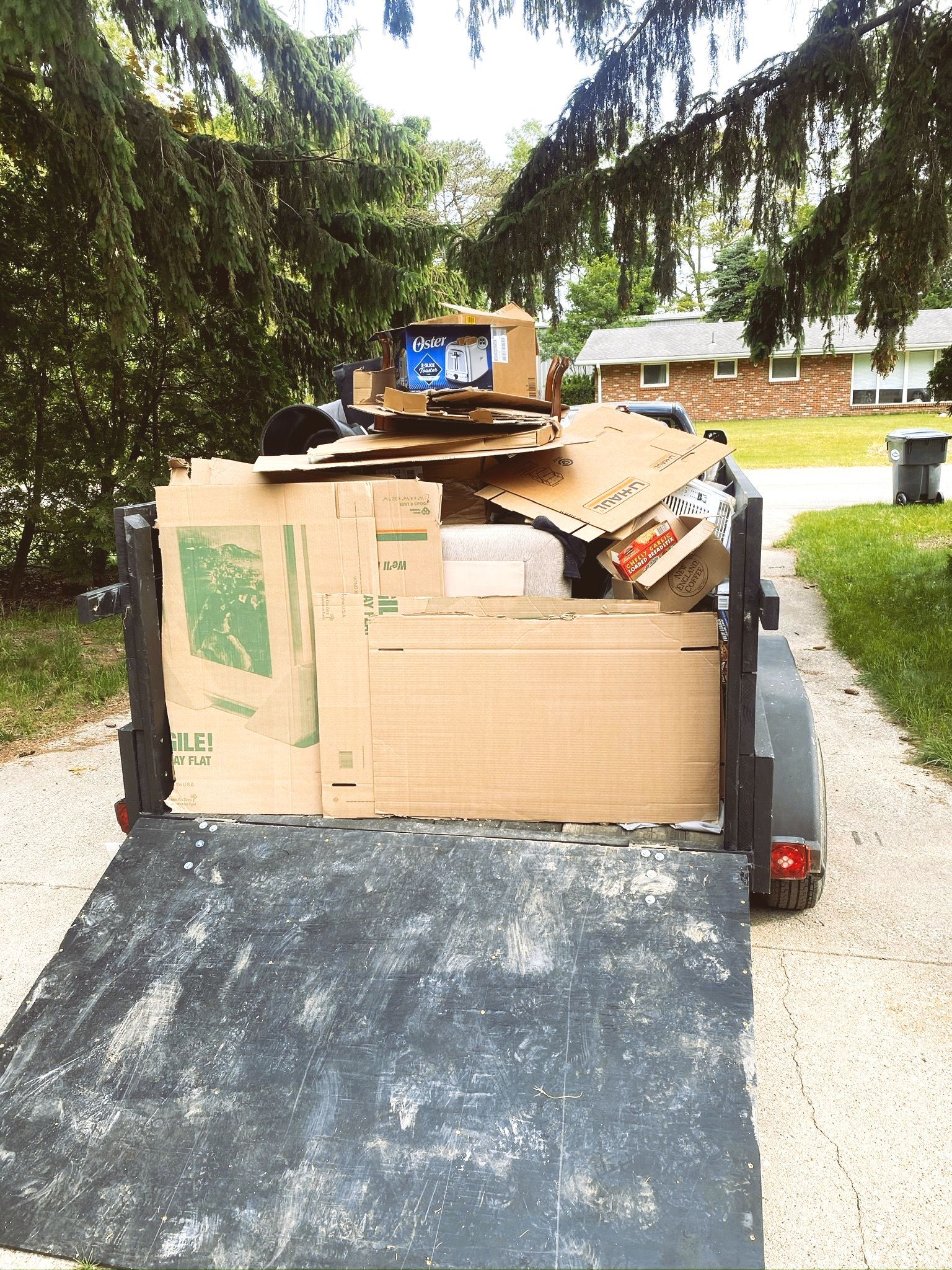 A trailer filled with cardboard boxes is parked on the side of the road