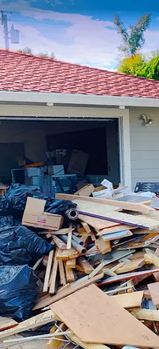 A pile of wood is sitting in front of a garage door.