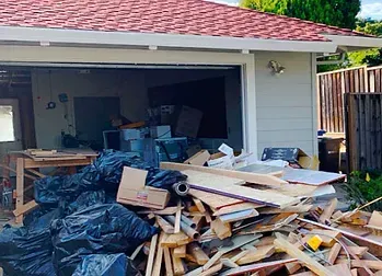 A pile of wood is sitting in front of a garage door.