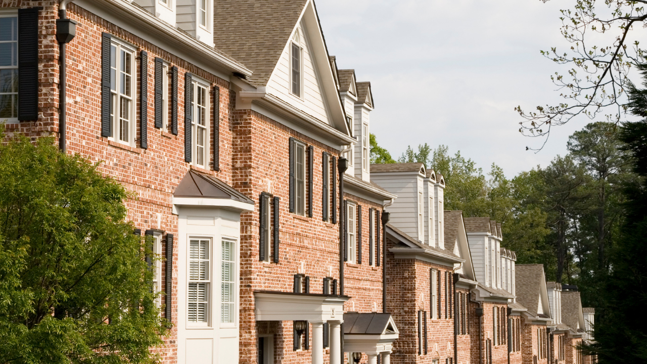 Row of brick townhouses with white-trimmed windows along a quiet street
