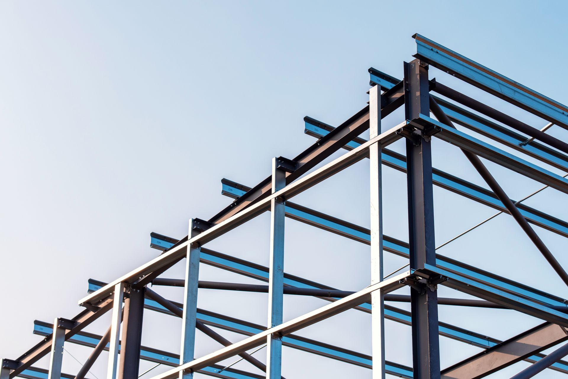 Steel beams forming the frame of a building under construction against a clear sky. Steel beams forming the frame of a building under construction against a clear sky.
