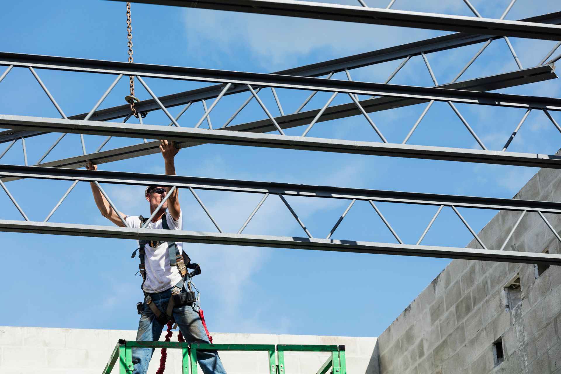 A man is standing on a ladder working on a metal structure.