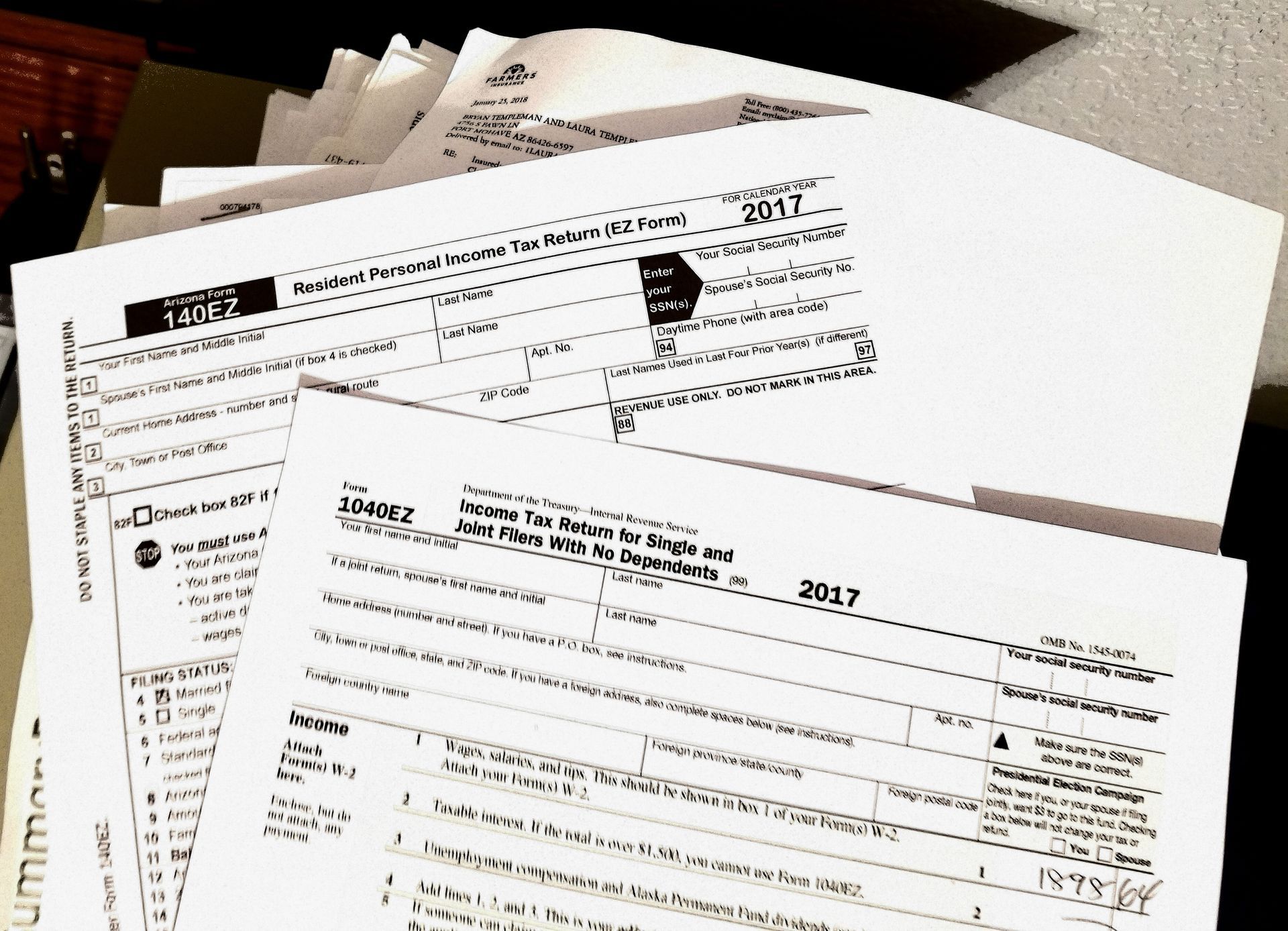 Pile of 2017 tax forms, including Schedule A and 1040 forms, on a desk.