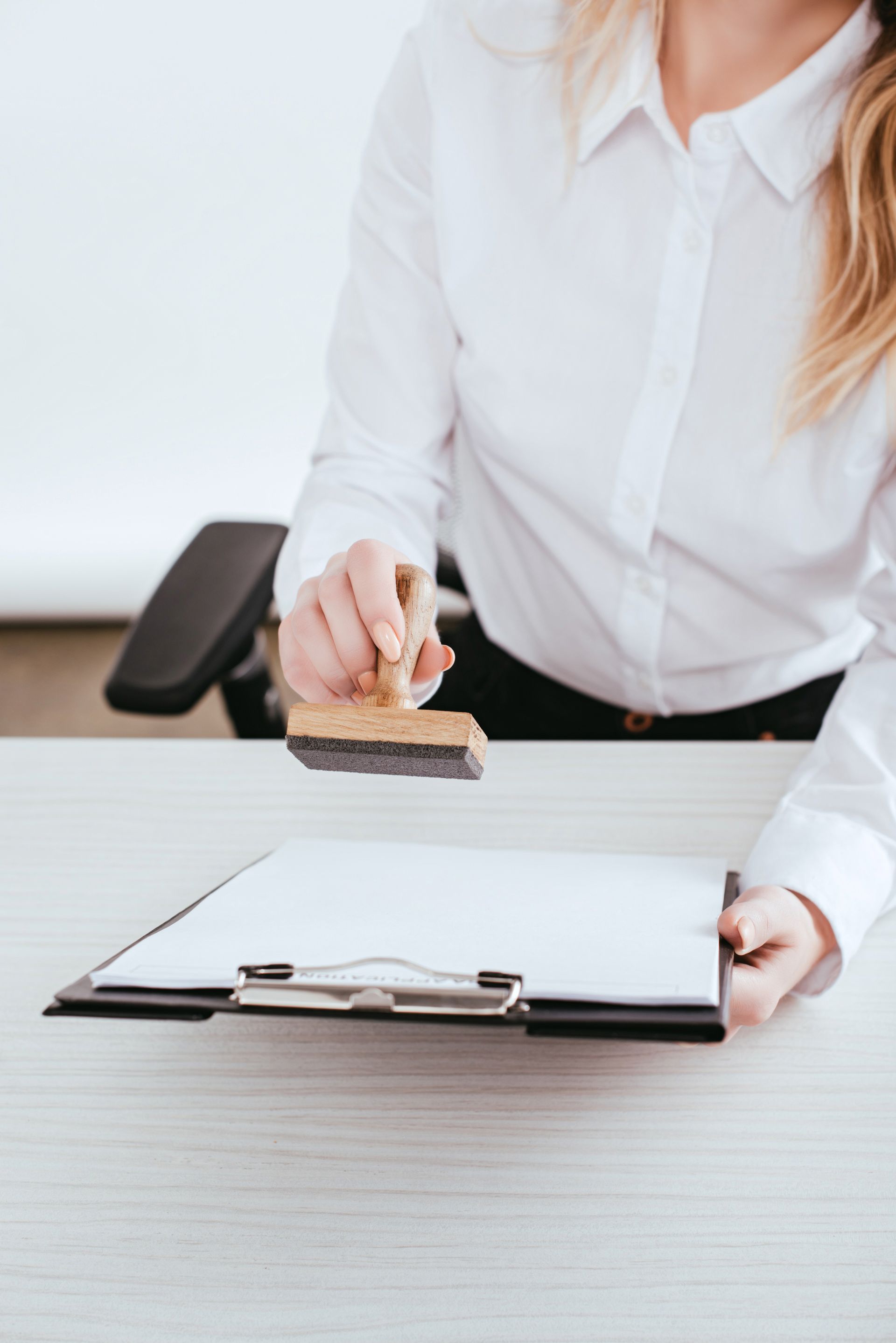 Woman stamping a document on a clipboard at a desk.