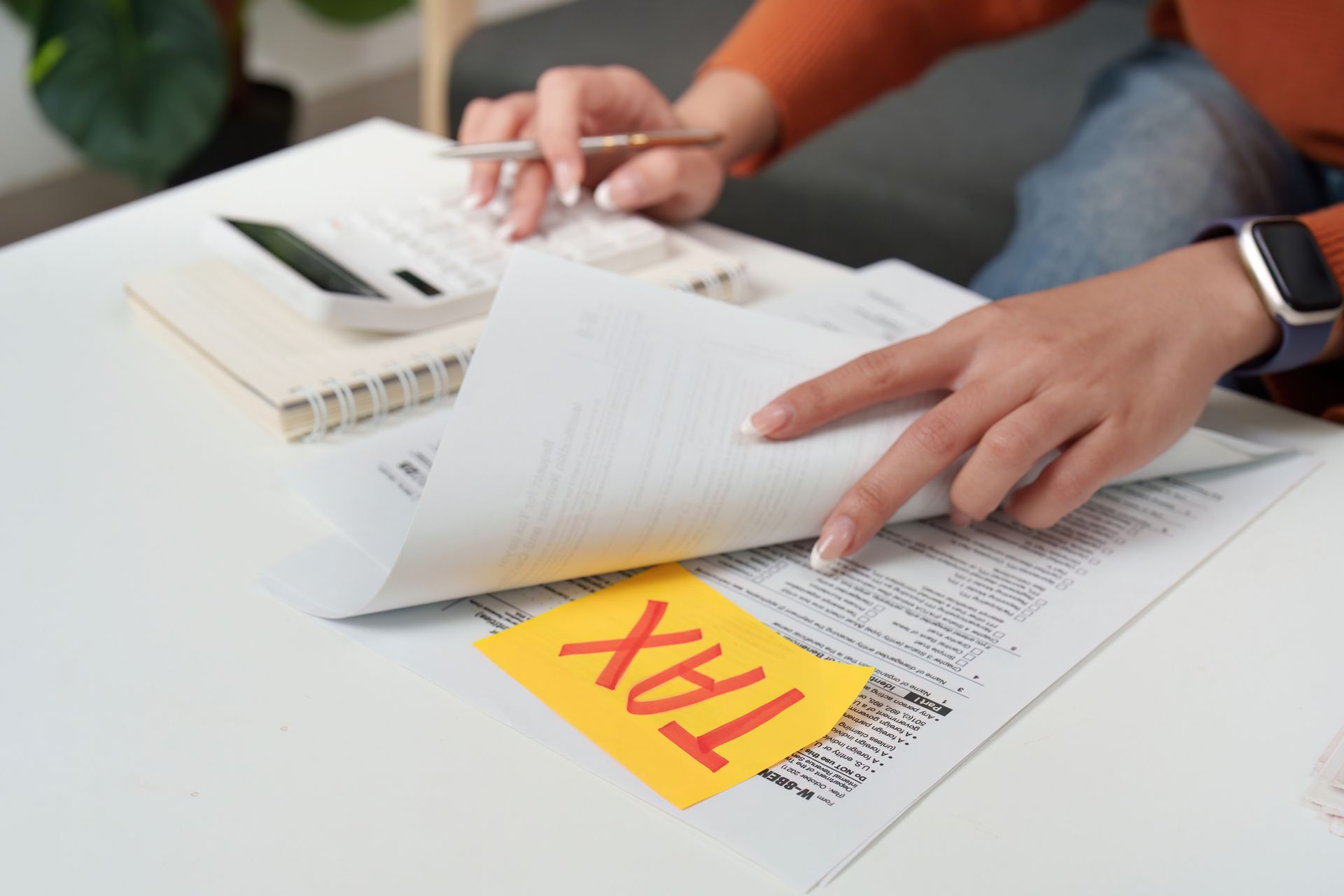Person working on tax documents, holding a pen. A 