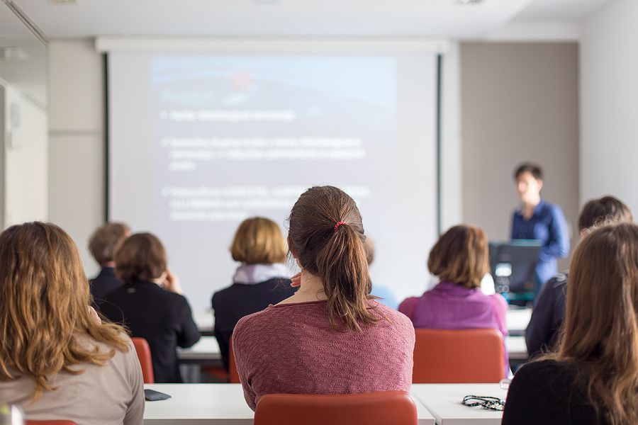 A group of people are sitting in a classroom watching a presentation.