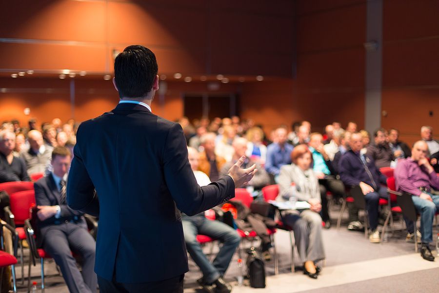A man is giving a presentation to a large group of people in a conference room.