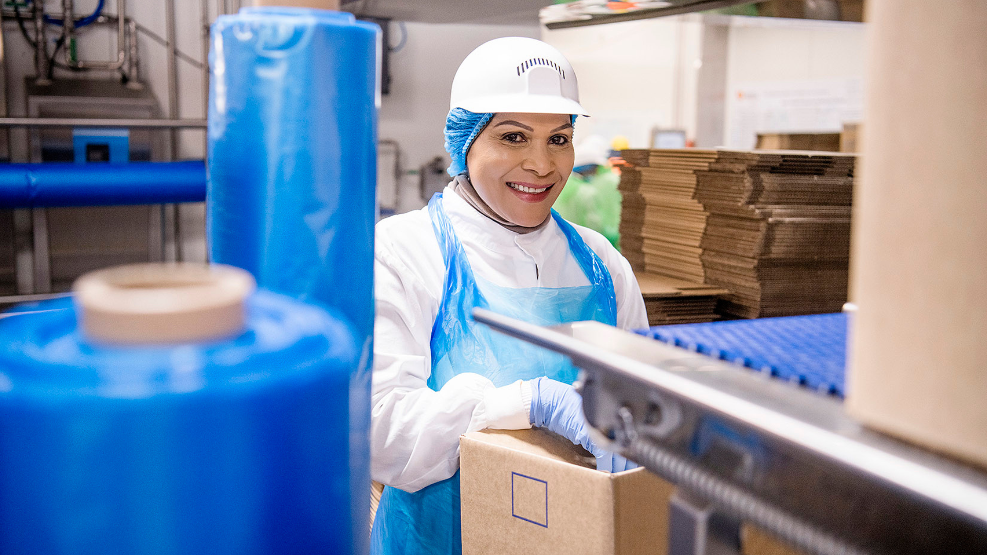Three people in orange workwear on a construction site. One holds a shovel.