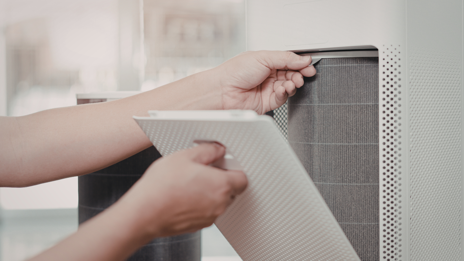 Person removing an air purifier filter.
