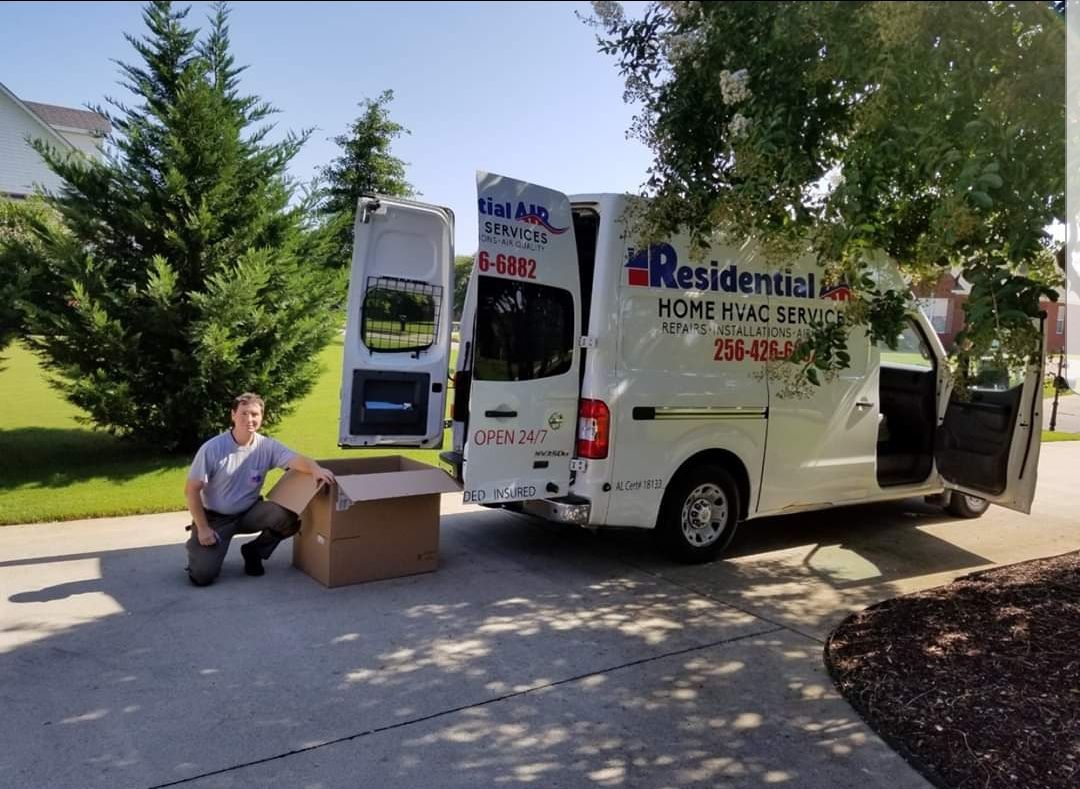 Man kneels next to a cardboard box near a van labeled