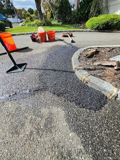 A person is laying asphalt on the side of a road.