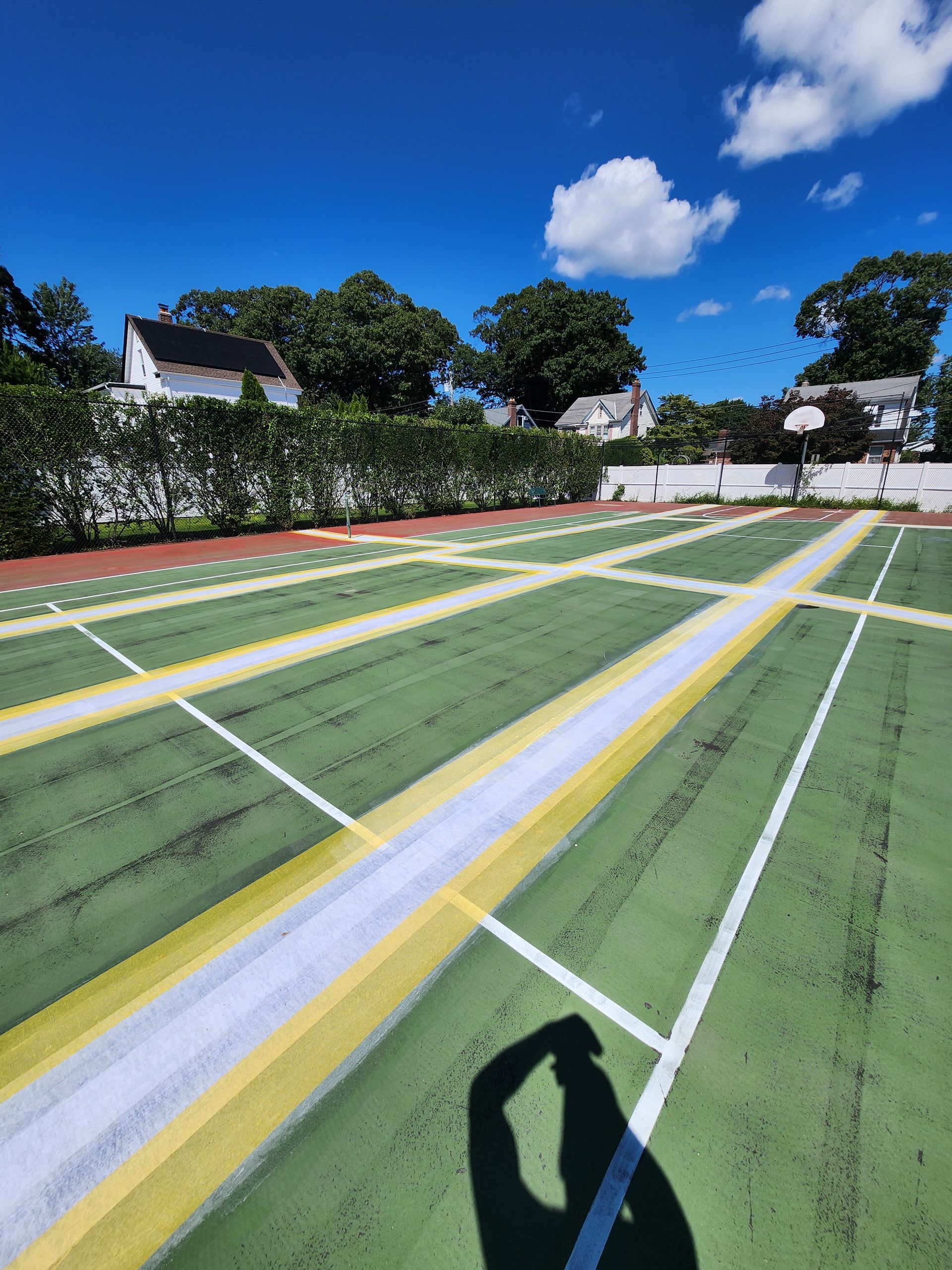A shadow of a person is cast on a tennis court